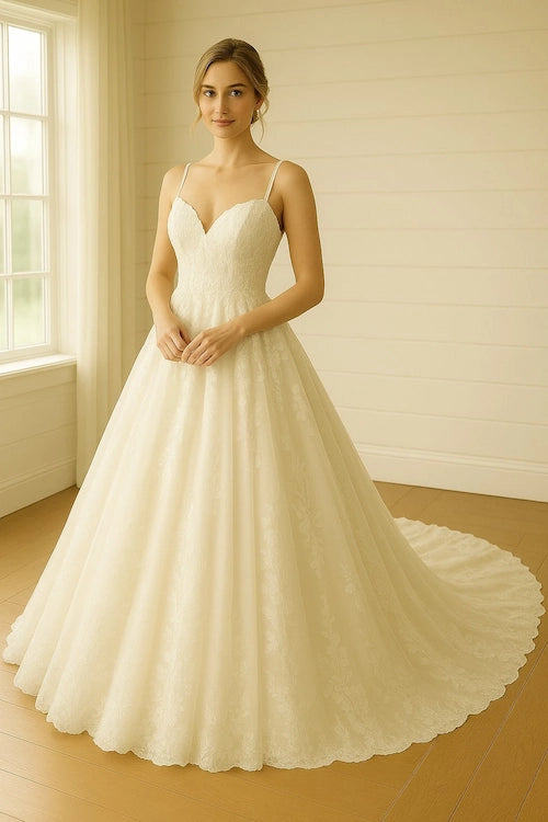 A woman modeling a white A-line wedding gown with thin spaghetti straps, a sweetheart neckline, and a full skirt with a long train - a typical example of a grande wedding dress clean